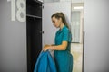 Long-haired young female doctor putting her clothes to the locker