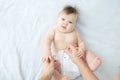 Changing diaper on baby girl on bed, changing nappy, smiling baby portrait Royalty Free Stock Photo