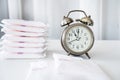 Changing Pads, don\'t wear a pad too long concept with an alarm clock and menstrual pads on the table