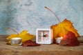 Changing from summer to winter time in October, small alarm clock set back one hour, autumn leaves and candles on rustic wood, Royalty Free Stock Photo