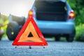 Changing tire on broken down car on a road with red warning triangle Royalty Free Stock Photo