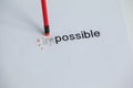 Changing the word impossible to possible with a pencil eraser
