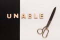 Changing word unable into able with scissors Royalty Free Stock Photo