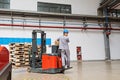 Changxing, China, 22 June 2019: Storehouse employee in uniform working on forklift in modern automatic warehouse.Boxes are on the