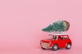 Changxing, China - October 15, 2019: Red toy car with a christmas tree on the roof on pink paper background. Winter delivery, xmas Royalty Free Stock Photo