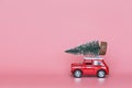 Changxing, China - October 15, 2019: Red toy car with a christmas tree on the roof on pink paper background. Winter delivery, xmas Royalty Free Stock Photo