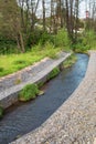 A channel made of granite stones for the river stream with grass and shrubs on the banks. Landscaping of the city, river