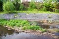 A channel made of granite stones for the river stream with grass and shrubs on the banks. Landscaping of the city, river