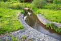 A channel made of granite stones for the river stream with grass and shrubs on the banks. Landscaping of the city, river