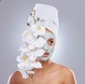 Channelling my inner beauty. an attractive young woman wearing a face mask and holding an orchid in the studio.