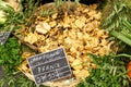 Chanterelle mushrooms in basket in French supermarket, labeled in French with price, surrounded by greenery.