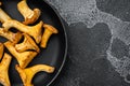 Chanterelle mushrooms, in cast iron frying pan, on black dark stone table background, top view flat lay, with copy space for text Royalty Free Stock Photo