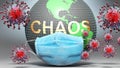 Chaos and covid - Earth globe protected with a blue mask against attacking corona viruses to show the relation between Chaos and