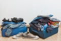 Chaotic blue suitcase with a lot of clothing, preparing for vacations, white background