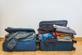 Chaotic blue suitcase with a lot of clothing, preparing for vacations, white background