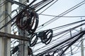 Chaotic Intertwining mess of electricity power lines on pole in Thailand