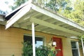 Chaotic looking front porch sagging rotting wood exterior light on red front door Royalty Free Stock Photo