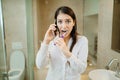 Chaotic preparation for work in the morning.Young woman talking on the phone while brushing teeth and putting on clothes.Busy Royalty Free Stock Photo