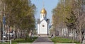 Chapel named after St. Nicholas the Wonderworker in Russian city of Novosibirsk is white with a golden dome next to a bench in an Royalty Free Stock Photo