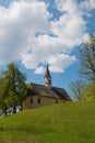 Chapel St Georg and trees at Weinberg hill, spring landscape Schliersee. blue sky with clouds