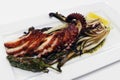 char grilled mediterranean style octopus tentacle with padron pepper, chicory and lemon wedges Royalty Free Stock Photo