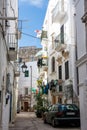 Characteristic alley with clothes hanging out to dry and parked car in the center of Monopoli Puglia