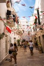 Characteristic alley with flags hanging and people tourists in the center of Monopoli Puglia