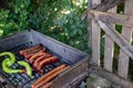 Charcoal BBQ with sausages and green papers on barbecue grill in country side house backyard Royalty Free Stock Photo