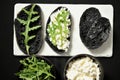 Charcoal black rye bread with cottage cheese and rocket on a black background