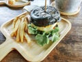 Charcoal burger made with black charcoal bun with potato french fries on wooden