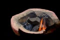 Charcoal on flame in brazier stove on black background