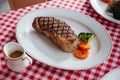 Charcoal grilled boneless wagyu Top Loin steak served with BBQ sauce and baked potato in white plate.