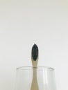 Charcoal infused bamboo toothbrush in glass with off white background