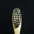 Charcoal infused bamboo toothbrush on shinny black background. Close up view, square photo image.