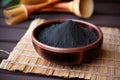 charcoal powder in a small bowl on a bamboo mat