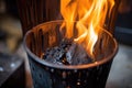 charcoals aflame in an upright chimney starter