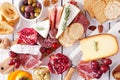 Charcuterie board of assorted cheeses, meats and appetizers, top view table scene over white wood Royalty Free Stock Photo