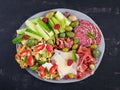 Charcuterie board. Platter: parmesan with prosciutto, salami, cucumbers and olives. Royalty Free Stock Photo