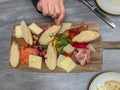 Charcuterie board with woman`s hand reaching for slice of bread Royalty Free Stock Photo