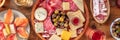 Charcuterie and cheese platter panorama with wine and salmon sandwiches Royalty Free Stock Photo