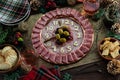 A Charcuterie platter made into a clock surrounded by festive decorations and food.