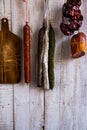 Charcuterie, variety of sausages hanging on hook, wood cutting board, string with dry peppers nyora, Spanish meat delicacies Royalty Free Stock Photo