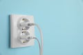 Charger adapters plugged into power sockets on light blue wall, space for text. Electrical supply Royalty Free Stock Photo
