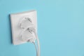 Charger adapters plugged into power sockets on light blue wall, space for text. Electrical supply Royalty Free Stock Photo