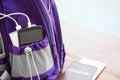 Charging mobile phone with power bank in purple backpack and passport on table, closeup. Space for text Royalty Free Stock Photo