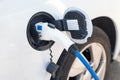 Charging modern electric car on the street. Electric car at charging station with power cable supply plugged in on blurred nature Royalty Free Stock Photo