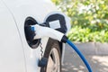 Charging modern electric car on the street. Electric car at charging station with power cable supply plugged in on blurred nature Royalty Free Stock Photo