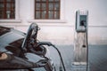 Power supply for hybrid electric car charging battery on urban europe street with blurred nature background. Eco car Royalty Free Stock Photo