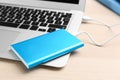 Charging modern laptop with power bank on table, closeup Royalty Free Stock Photo