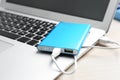 Charging modern laptop with power bank on table, closeup Royalty Free Stock Photo